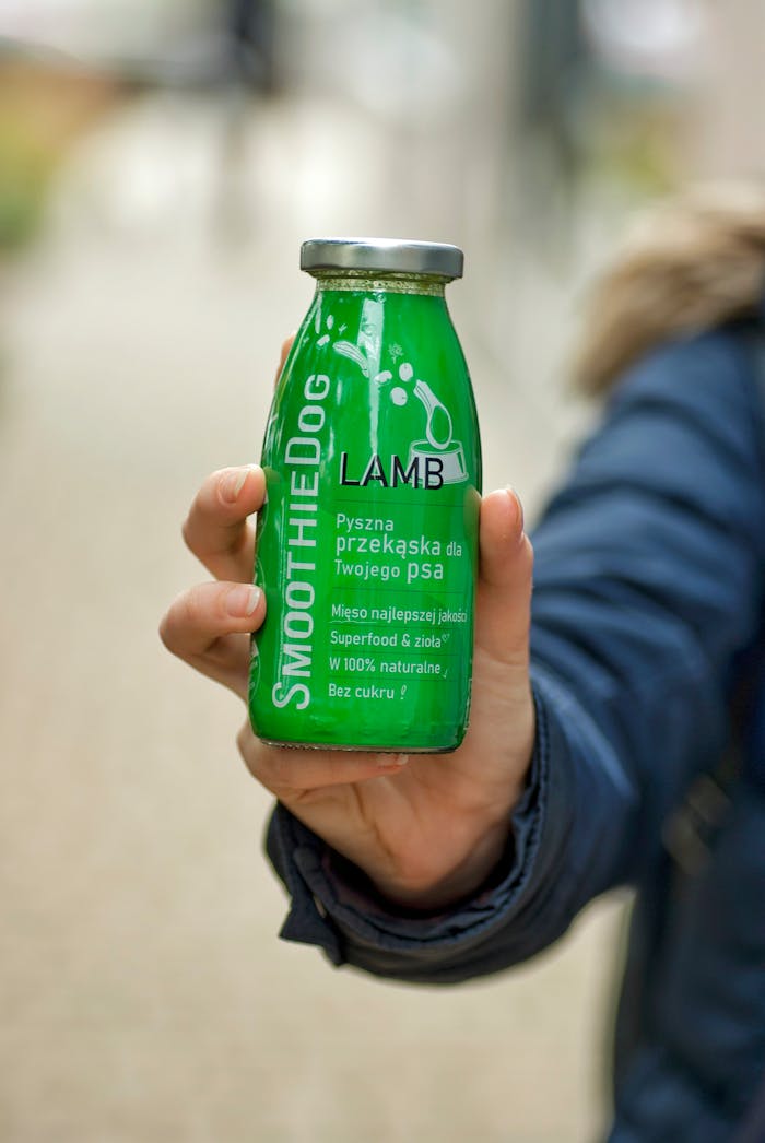 get-in-touch Hand holding a green smoothie bottle for dogs, showcasing natural pet treat.